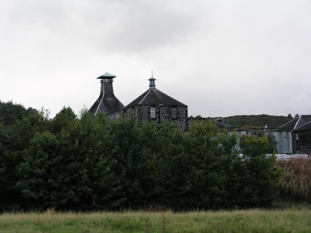 Historische Gebäude der ehemaligen Convalmore Distillery hinter Bäumen und Sträuchern